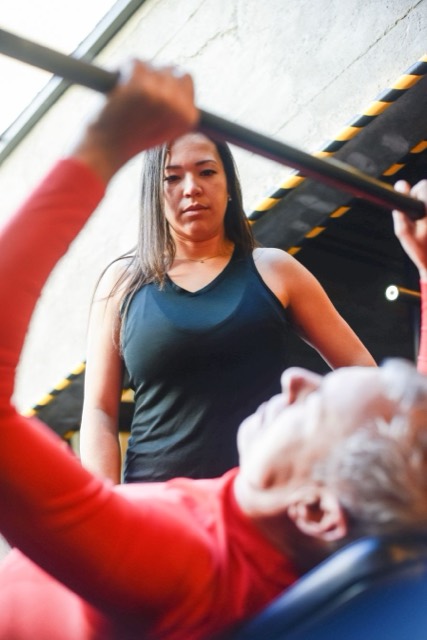 Personal trainer dando suporte durante supino com barra