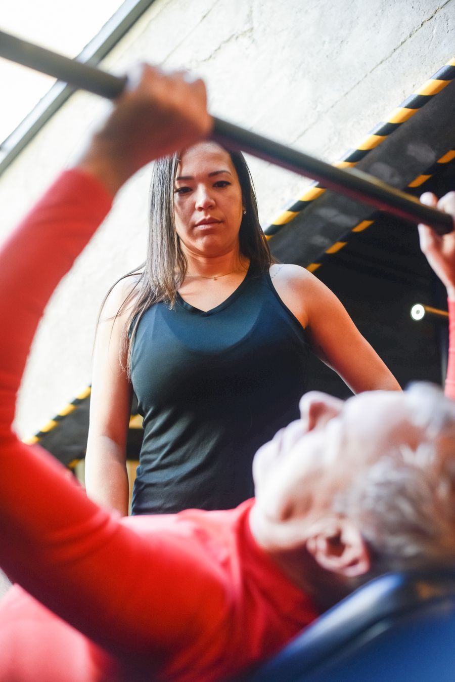 Personal trainer dando suporte durante supino com barra